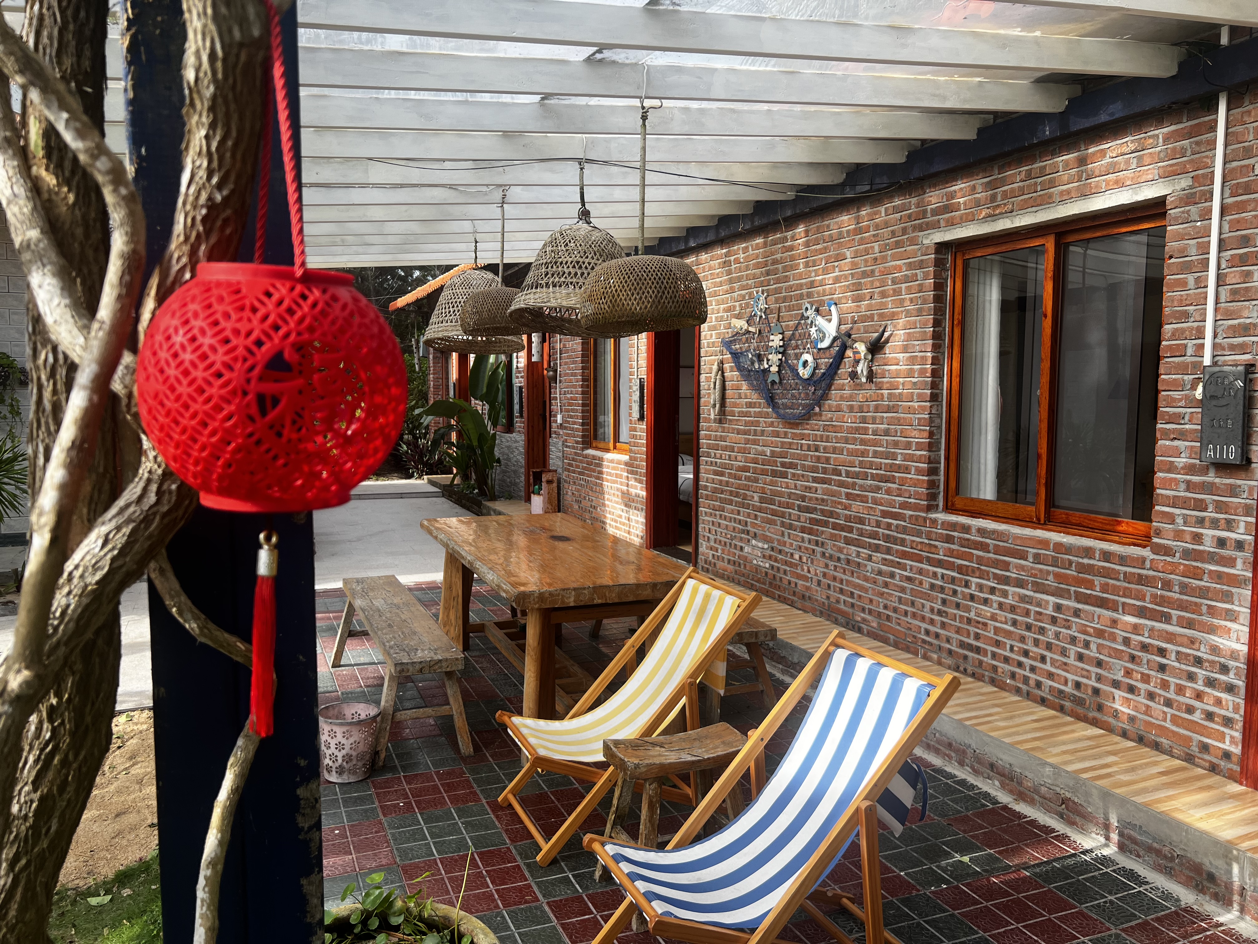 Outdoor courtyard with striped deck chairs, red lantern, and brick architecture