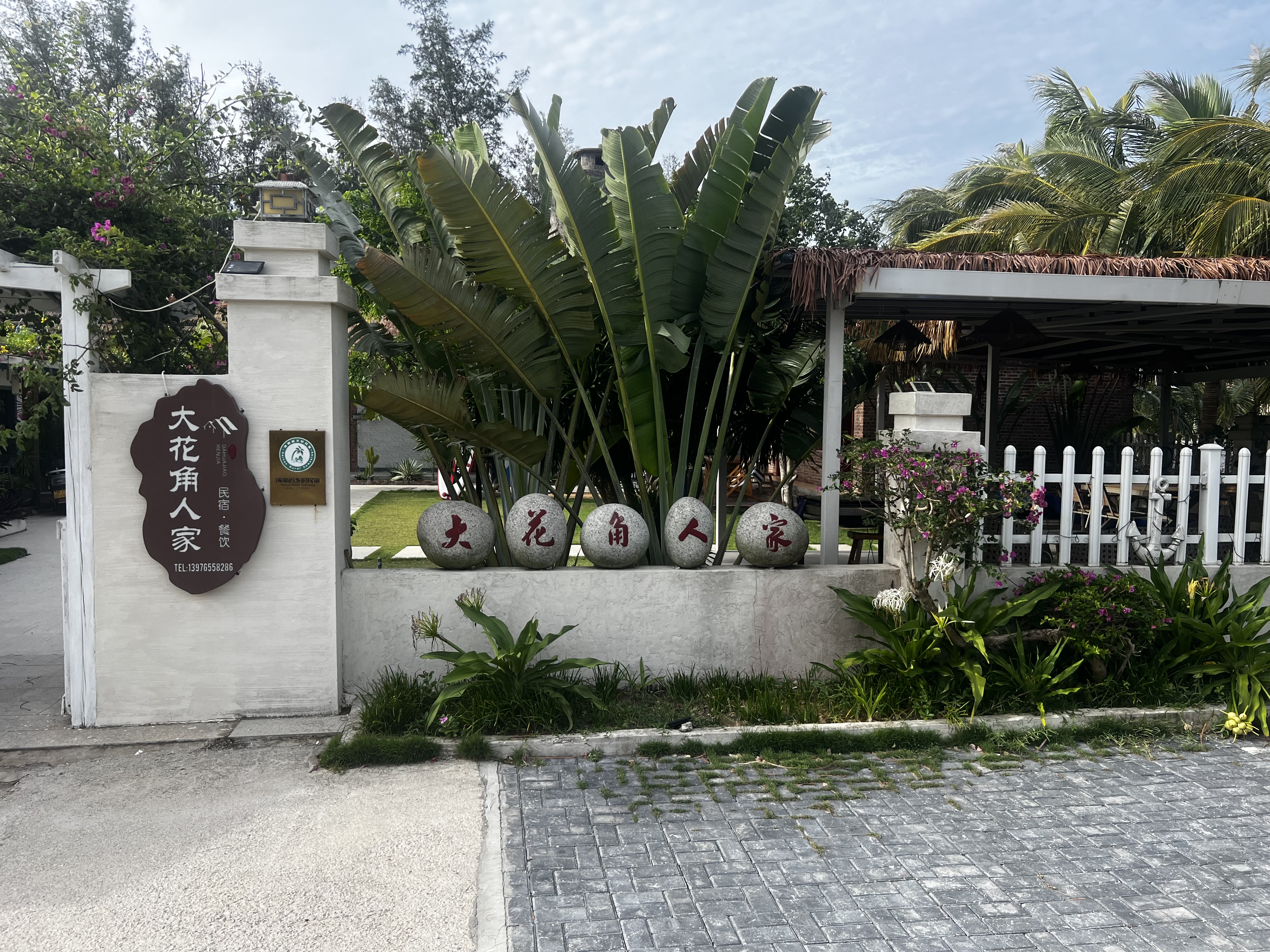 Dahuajiao Renjia entrance with tropical gardens and stone markers